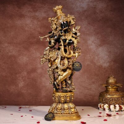 Intricate floral patterns adorn the base of the Krishna statue, showcasing exquisite craftsmanship in brass.