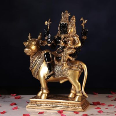 The intricately carved cow supports the Shiva Parvati idol, showcasing detailed attire and serene expressions.