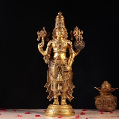 Front view of golden metal Venkateshwar statue with detailed carvings on black background