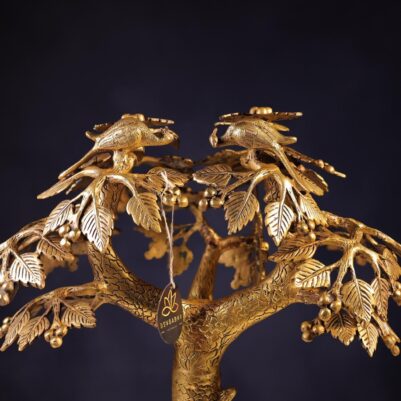Intricately detailed birds perched on leafy branches of a brass large tree sculpture