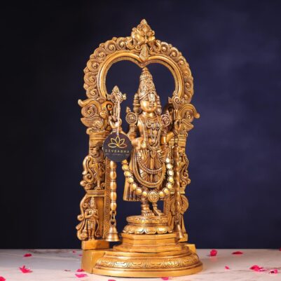 Intricate floral patterns carved on the arch frame surrounding the large brass Balaji statue standing upright