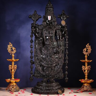 Intricate floral carvings adorn the dark black stone Tirupati Balaji idol standing upright.