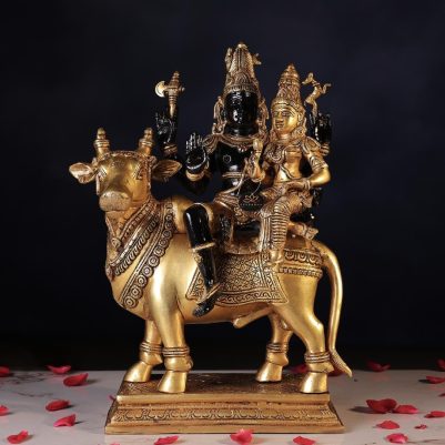 A brass idol of Shiva and Parvati seated on a decorative cow, showcasing intricate details and vibrant colors.